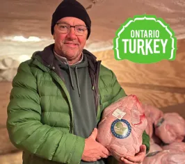 Rob Brady holding a fresh Scotch Line Turkey Company turkey, with the Ontario Turkey logo